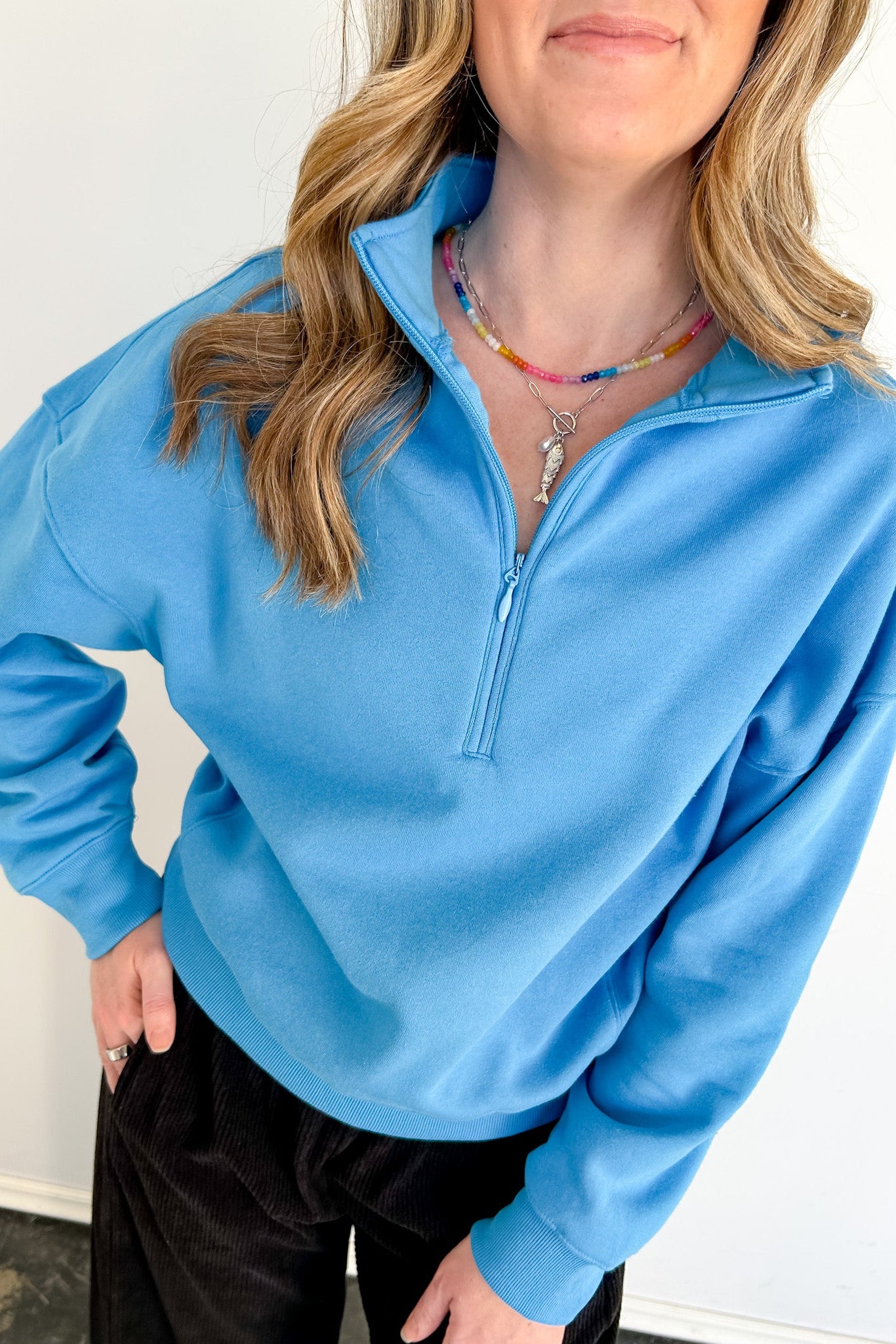 Person wearing a blue pullover with a zipper against a white background