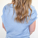 Light blue sleeveless top worn by a person with long blonde hair on a white background