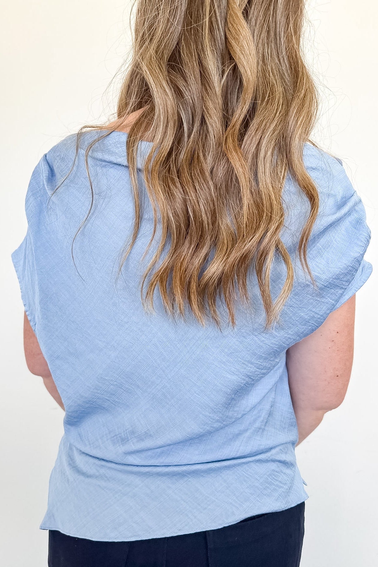 Light blue sleeveless top worn by a person with long blonde hair on a white background