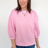 Woman wearing a pink sweatshirt and blue jeans against a white background