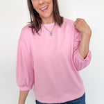 Woman wearing a pink sweater and blue jeans against a white background