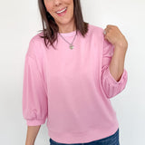 Woman wearing a pink sweater and blue jeans against a white background