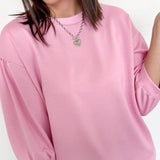 Woman wearing a pink sweater and blue jeans against a white background