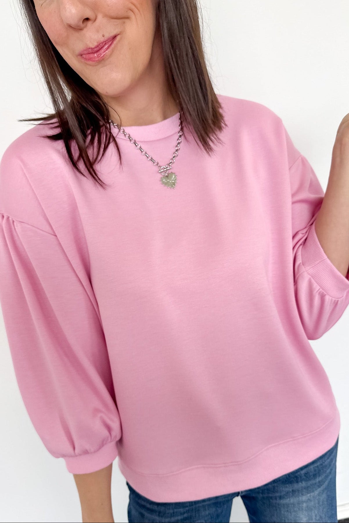 Woman wearing a pink sweater and blue jeans against a white background