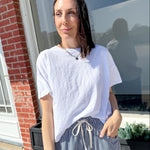 Woman wearing a white t-shirt and striped pants standing outside a building.