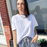 Woman wearing a white t-shirt and striped pants standing outside a building.