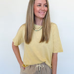 Woman wearing a yellow shirt and striped pants against a white background