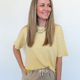 Woman wearing a yellow shirt and striped pants against a white background