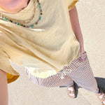 Person wearing a yellow top and striped pants on a sidewalk