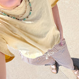 Person wearing a yellow top and striped pants on a sidewalk