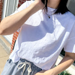 Person wearing a white textured shirt and blue striped pants outdoors.