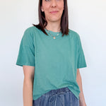 Woman wearing a green t-shirt and blue jeans against a white background
