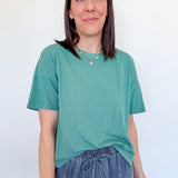 Woman wearing a green t-shirt and blue jeans against a white background