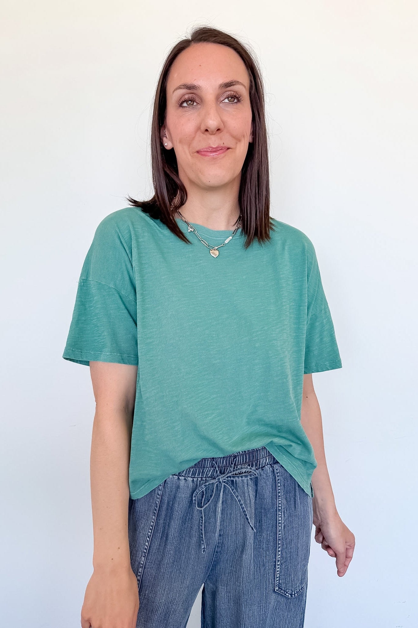 Woman wearing a green t-shirt and blue jeans against a white background
