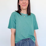 Woman wearing a green t-shirt and blue jeans against a white background