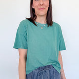 Woman wearing a green t-shirt and blue jeans against a white background