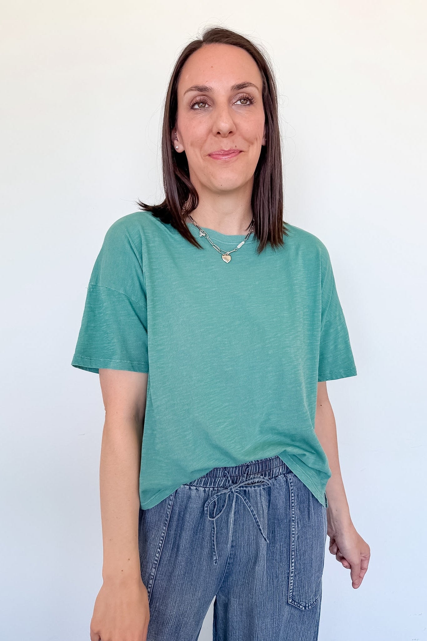 Woman wearing a green t-shirt and blue jeans against a white background