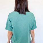 Person wearing a teal t-shirt and blue jeans against a white background