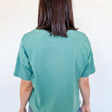Person wearing a teal t-shirt and blue jeans against a white background