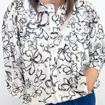 Photo of model wearing a black and white button down blouse