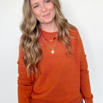 Woman wearing an orange sweater and blue jeans against a white background