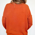 Person wearing an orange sweater on a white background
