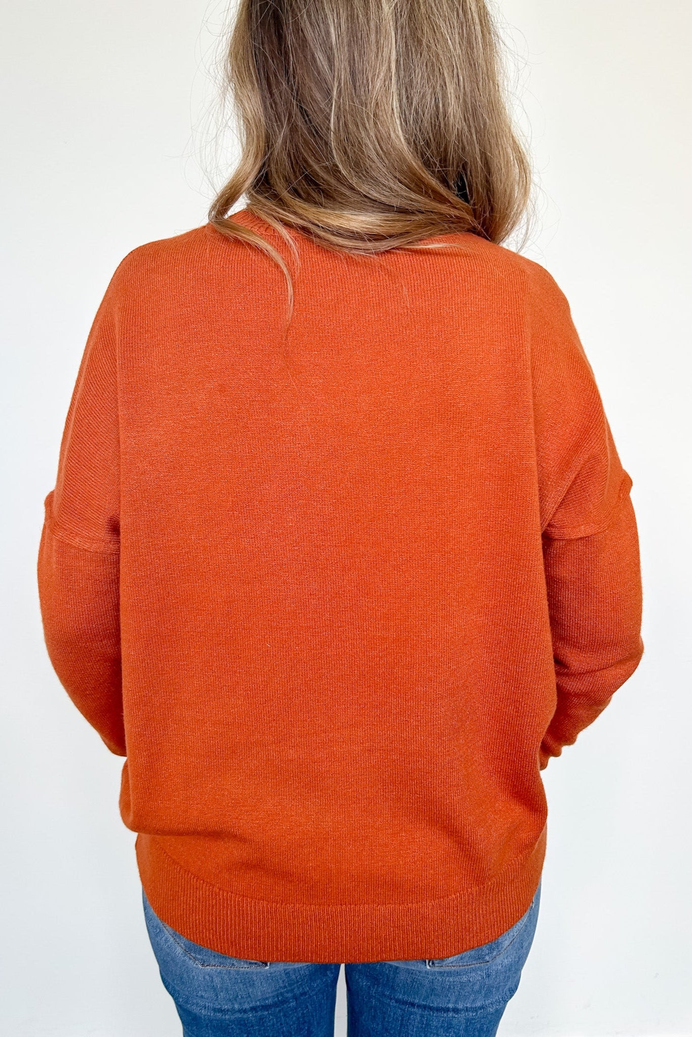 Person wearing an orange sweater on a white background