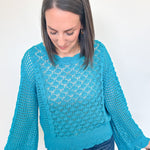 Woman wearing a blue knitted sweater against a white background
