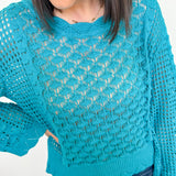 Person wearing a blue knitted sweater against a white background