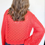 Person wearing a red crochet sweater against a white background