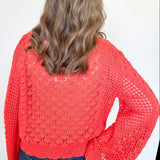 Person wearing a red crochet sweater against a white background