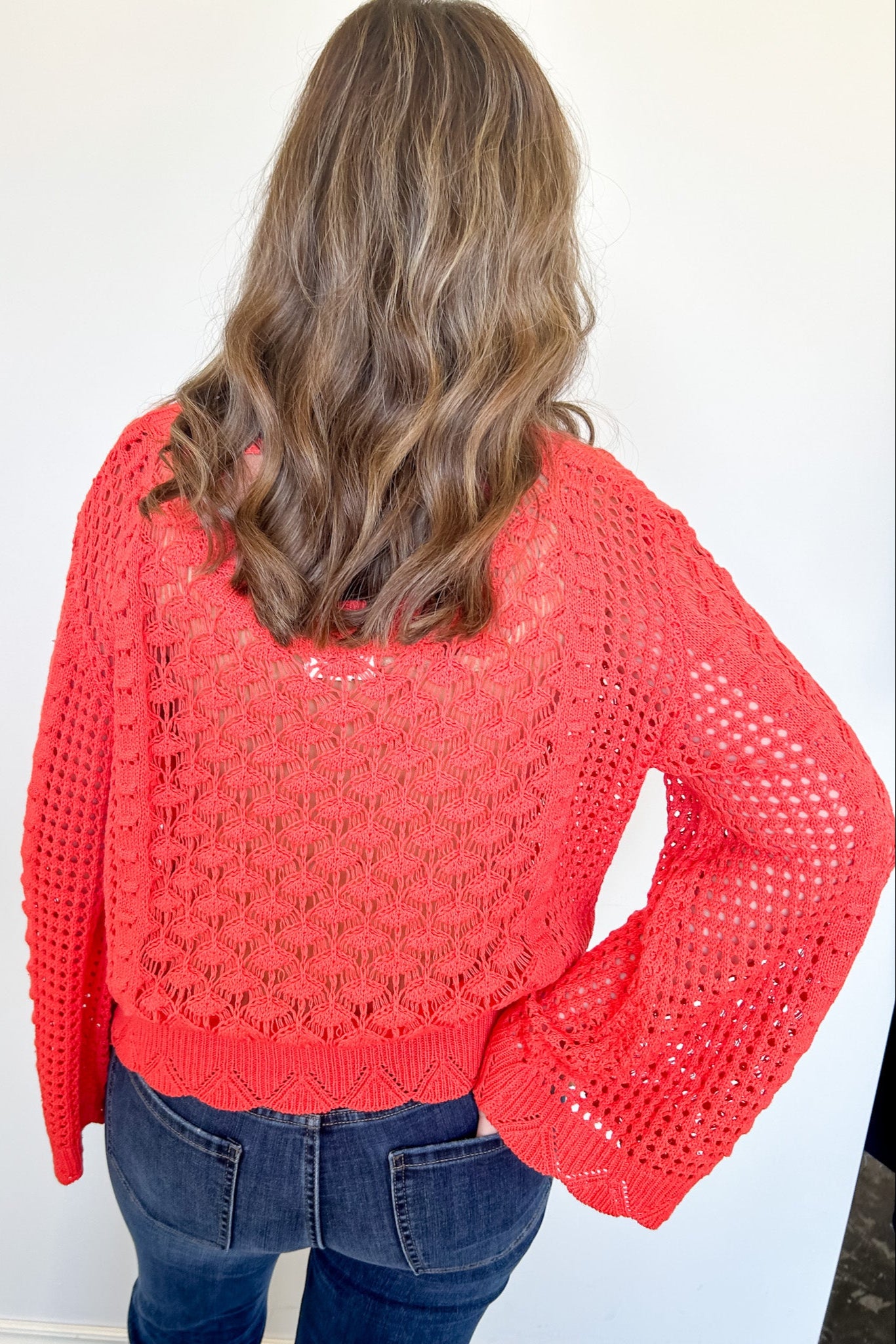 Person wearing a red crochet sweater against a white background