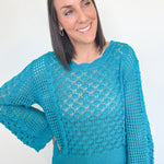 Woman wearing a blue crochet sweater against a white background