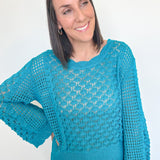 Woman wearing a blue crochet sweater against a white background