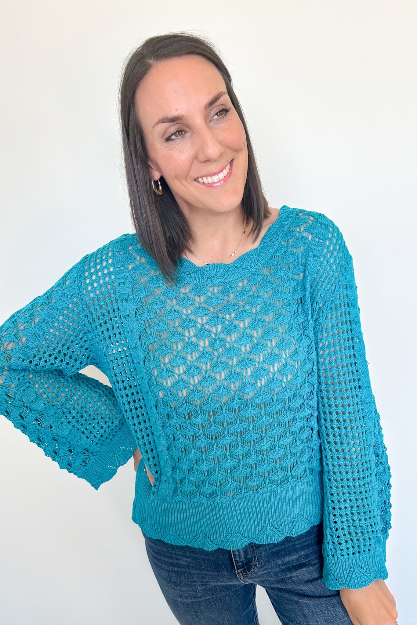 Woman wearing a blue crochet sweater against a white background
