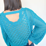 Person wearing a blue crochet sweater with a white background