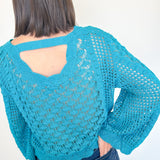 Person wearing a blue crochet sweater with a white background