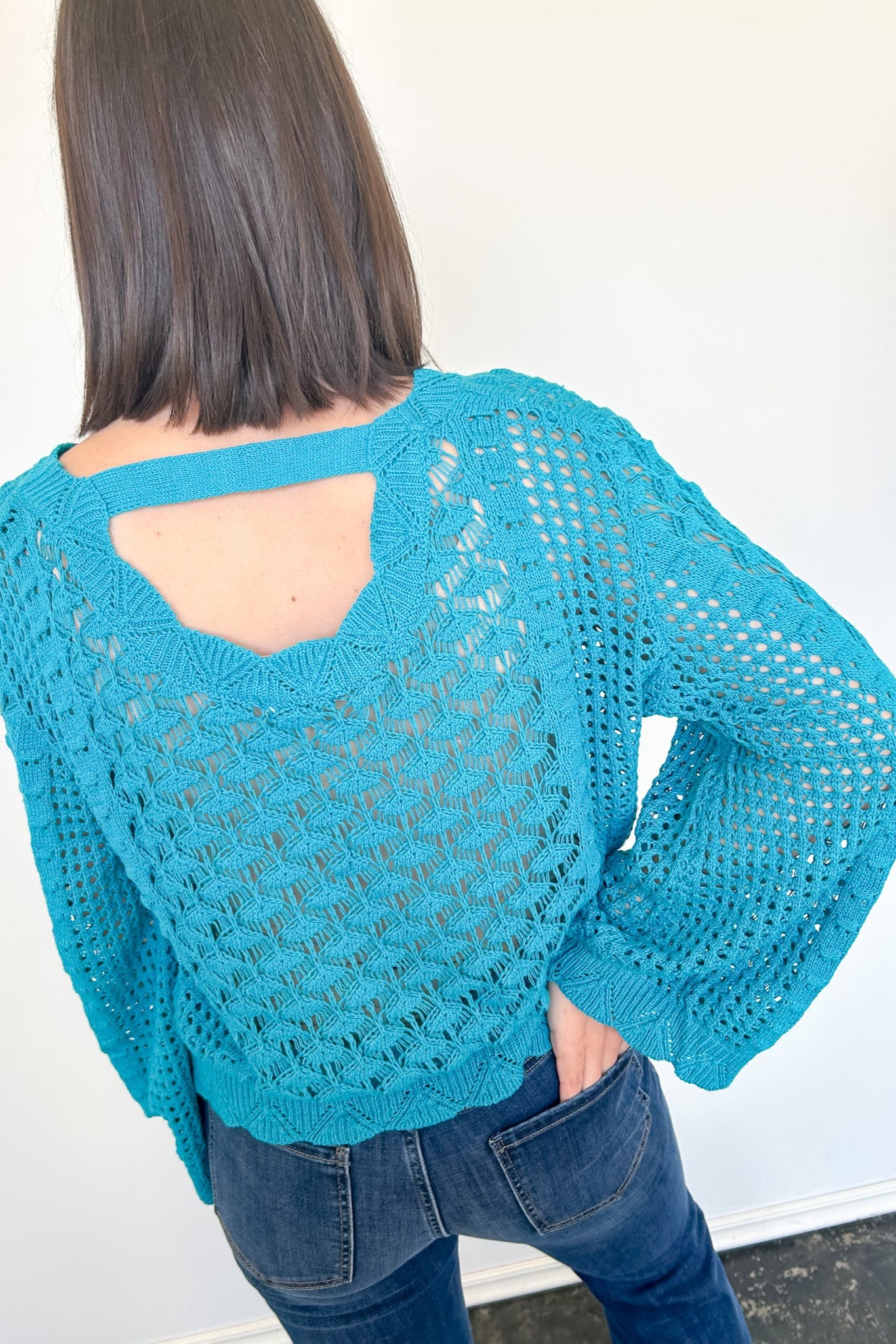 Person wearing a blue crochet sweater with a white background