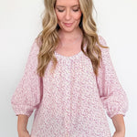 Woman wearing a pink floral blouse against a white background