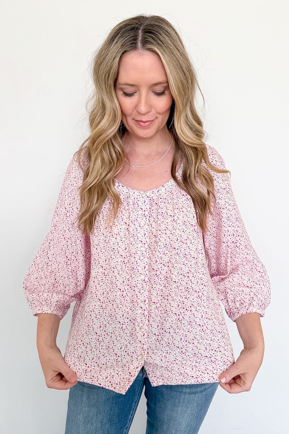 Woman wearing a pink floral blouse against a white background