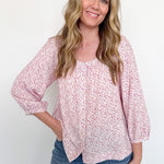 Woman wearing a pink floral blouse and blue jeans against a white background