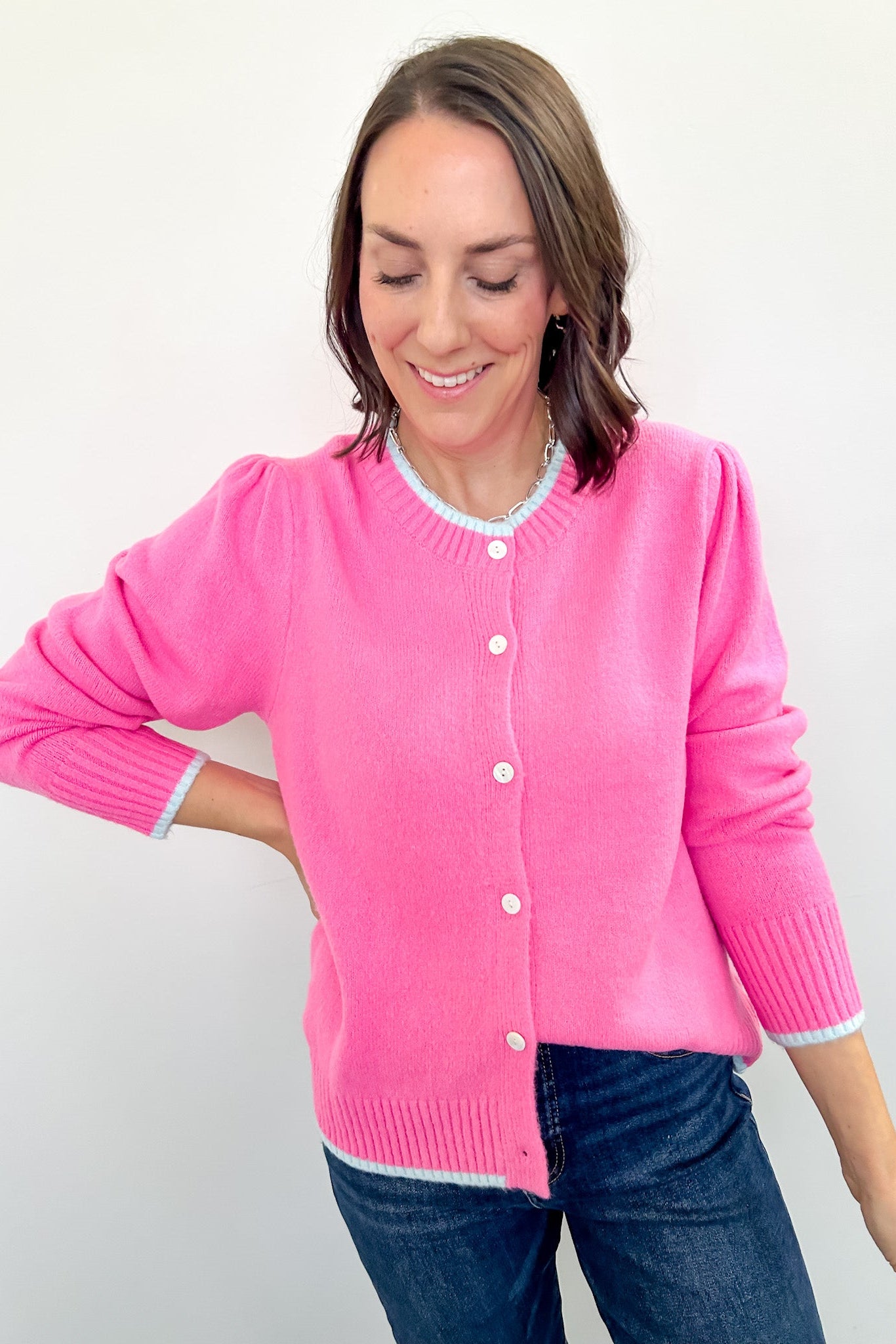 Woman wearing a pink cardigan against a white background