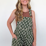 Woman wearing a green floral overalls against a white background
