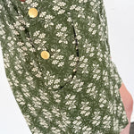 Green floral dress with gold buttons worn by a person on a white background