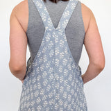 Person wearing a gray floral overalls with a plain background