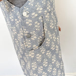 Close-up of a person wearing a gray floral-patterned vest with buttons.