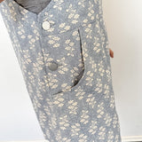 Close-up of a person wearing a gray floral-patterned vest with buttons.