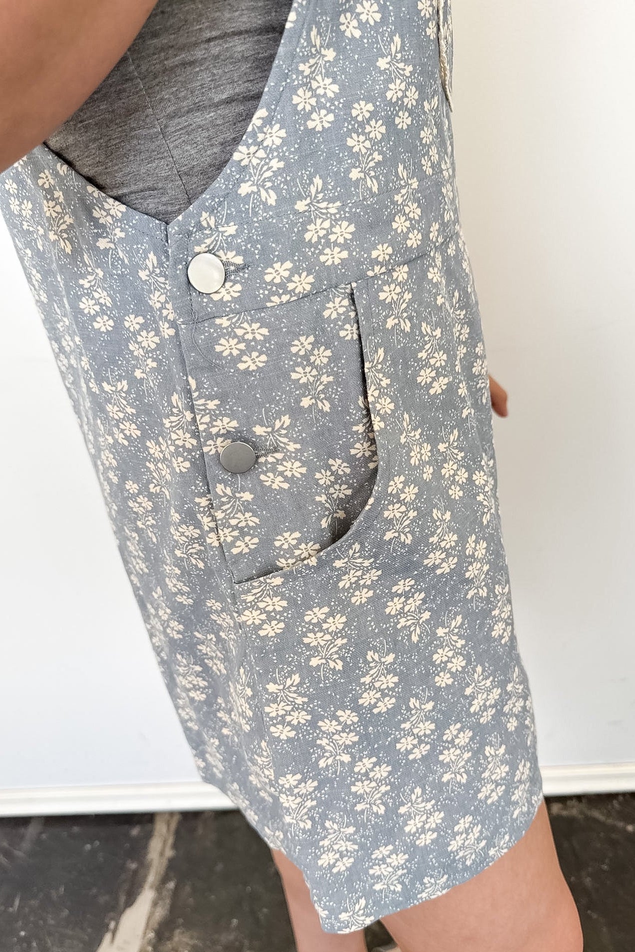 Close-up of a person wearing a gray floral-patterned vest with buttons.