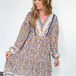 Woman wearing a long floral dress against a white wall