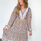 Woman wearing a long floral dress against a white wall